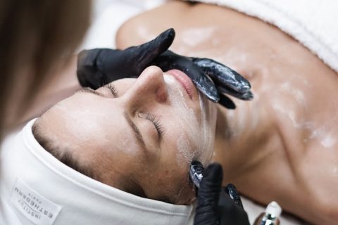Beautician Removing Clay Cosmetic Mask from Woman Face